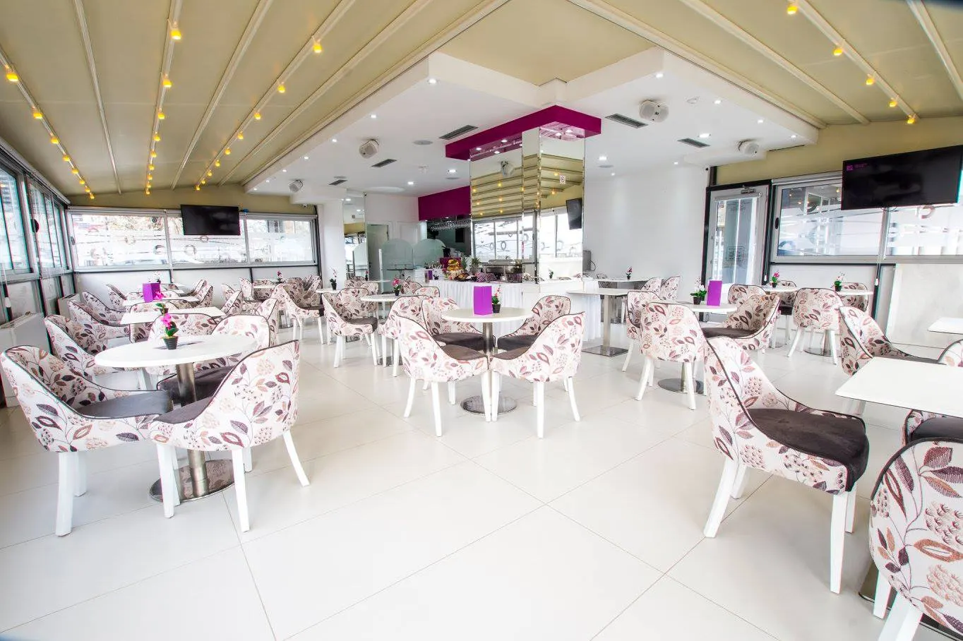 Bright Astera Coffee & Bar with floral armchairs and white tables